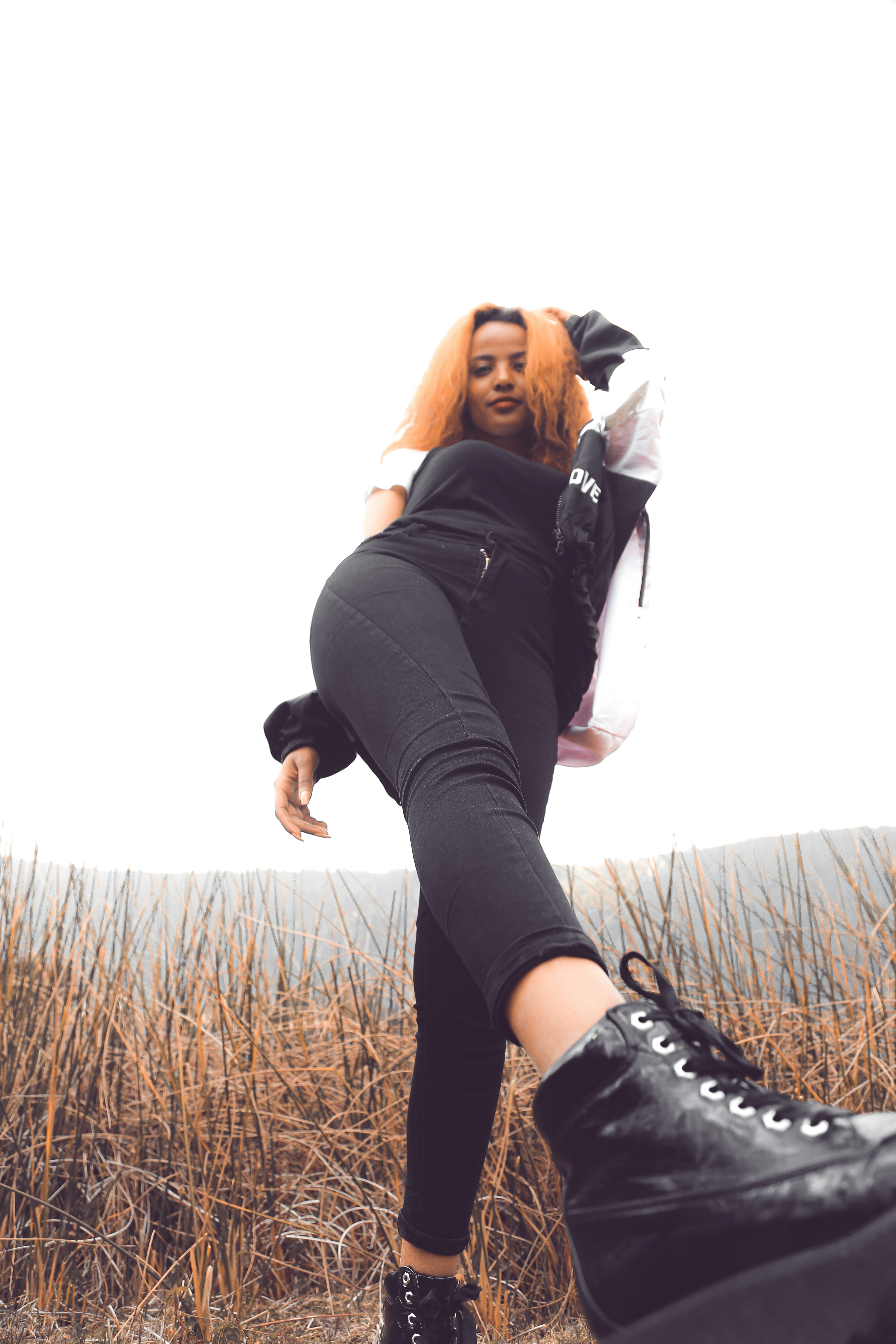 woman in black jacket and black leggings standing on brown grass field during daytime